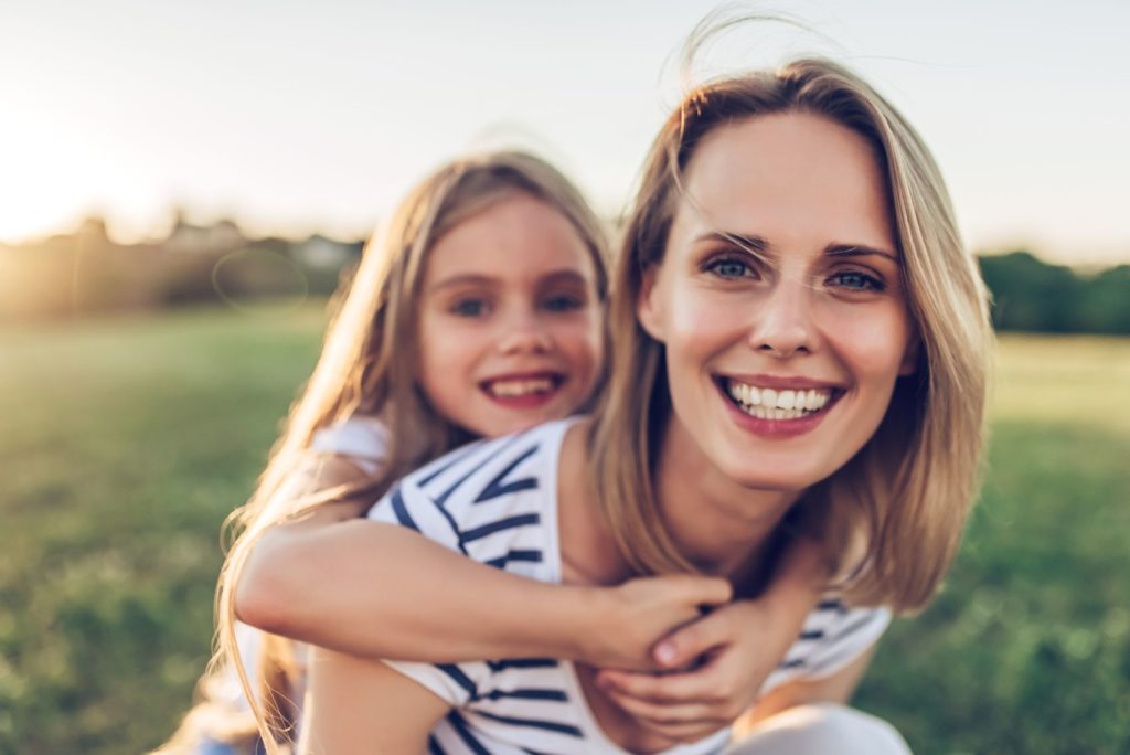 Mother and daughter smiling joyfully outdoors, showcasing beautiful smiles, representing the positive results of orthodontic treatment at Smiles to Love Orthodontics in Dublin.