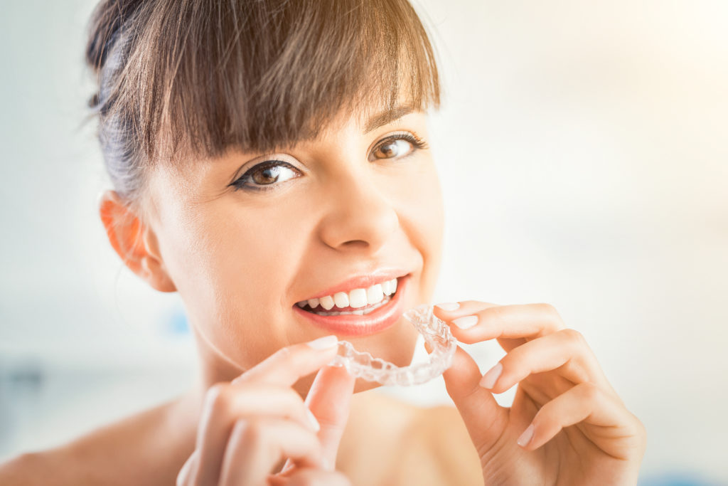 Patient holding clear aligner for Dublin Invisalign treatment